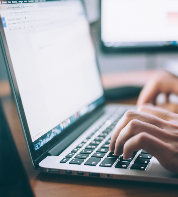 Hand typing on silver laptop