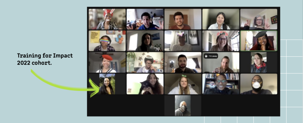 A virtual group photo of the Training for Impact 2022 cohort on a video call. Twenty-one participants appear in a grid of video tiles. A green illustrated arrow on the light blue background points to one participant in the lower left tile. Participants smile and wave at the camera.