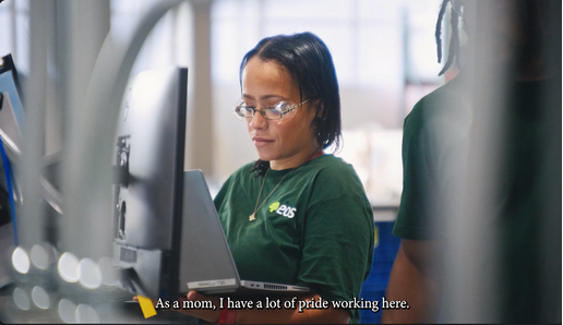 Screenshot of ad image. A woman wearing safety glasses holding a laptop.